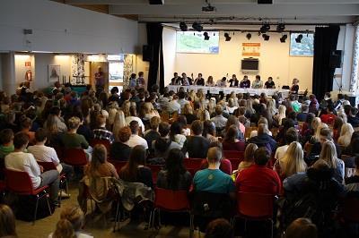 Oversiktsbilde fra en paneldebatt ved skolen med stort publikum og paneldeltakere i bakgrunnen - Klikk for stort bilde